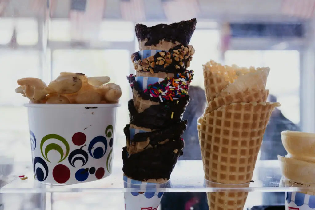 Decorated waffle cones dipped in chocolate and toppings displayed beside fresh waffle cones and ice cream treats at Buoy 18.