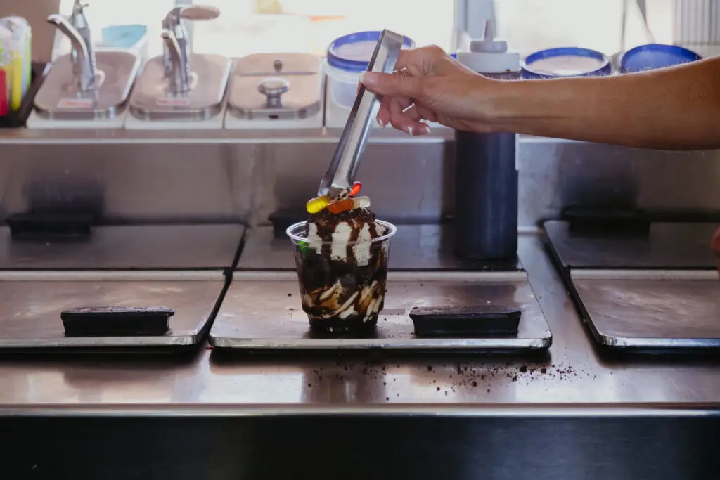Ice cream sundae being topped with gummy worms and cookie crumble at Buoy 18 in Bay City, Michigan.